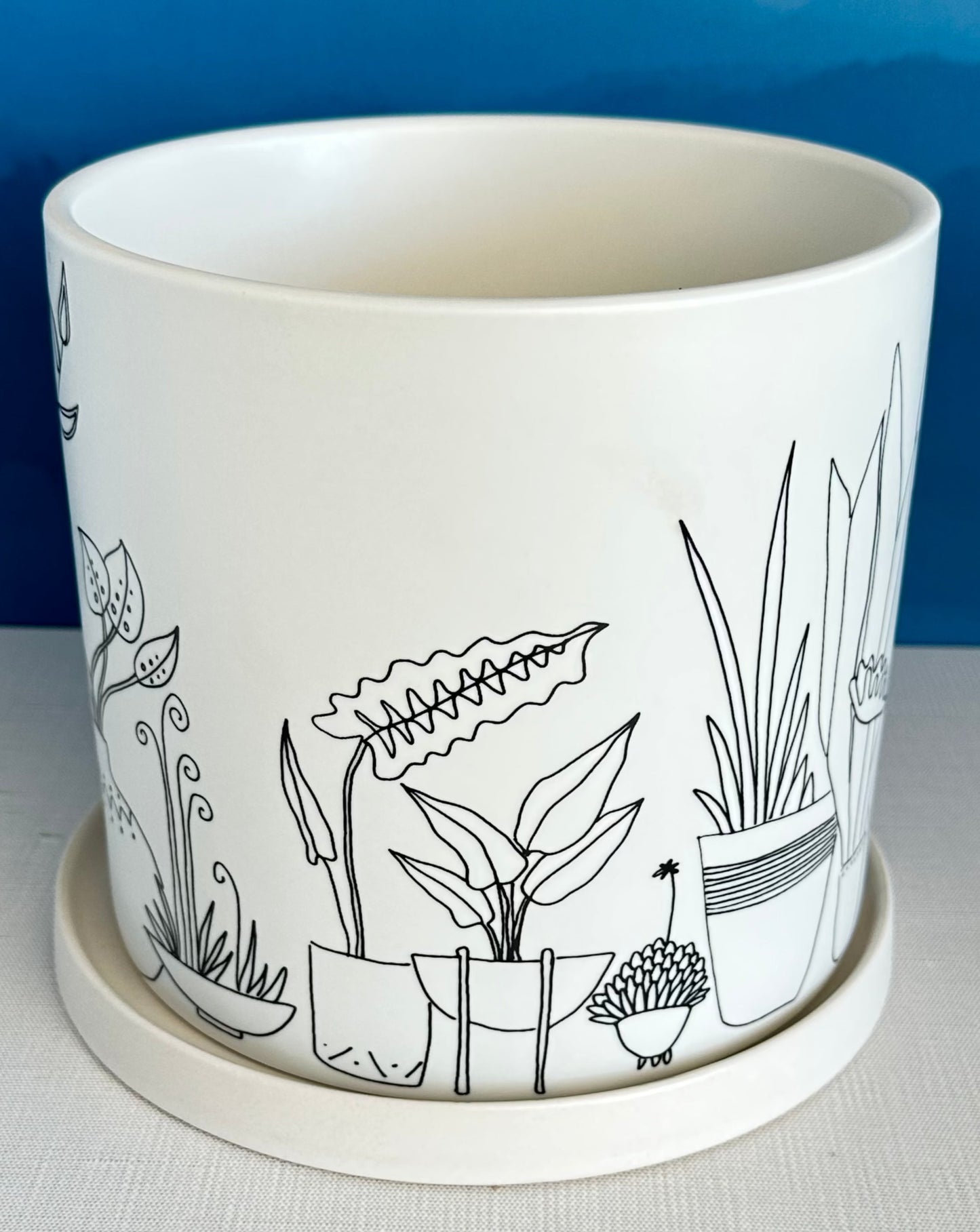 this large whimsical planter pot is covered with an illustrated jungle scene featuring all types of houseplants. A secret message sits on the rim inside: All I need is a little love and clean water