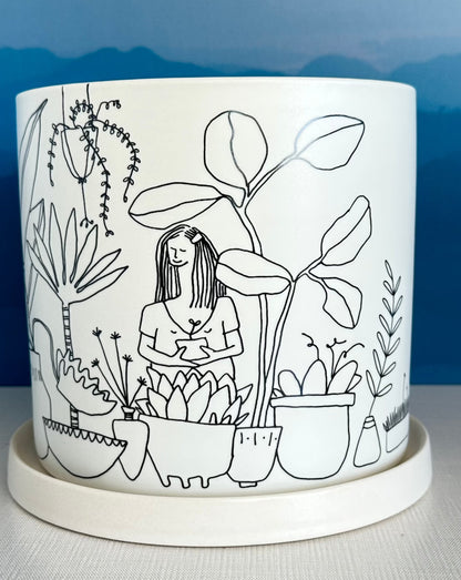 this large whimsical planter pot is covered with an illustrated jungle scene featuring all types of houseplants.  A secret message sits on the rim inside: All I need is a little love and clean water