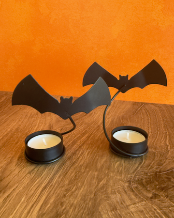 A set of 2 Halloween-themed bat-shaped tealight candle holders with two tea light candles, when lit these cast a dramatic shadow of flying bats on any wall. Made of Metal.
