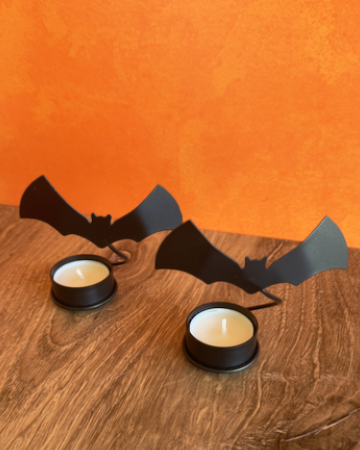 A set of 2 Halloween-themed bat-shaped tealight candle holders with two tea light candles, when lit these cast a dramatic shadow of flying bats on any wall. Made of Metal.