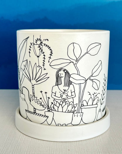 this large whimsical planter pot is covered with an illustrated jungle scene featuring all types of houseplants.  A secret message sits on the rim inside: All I need is a little love and clean water