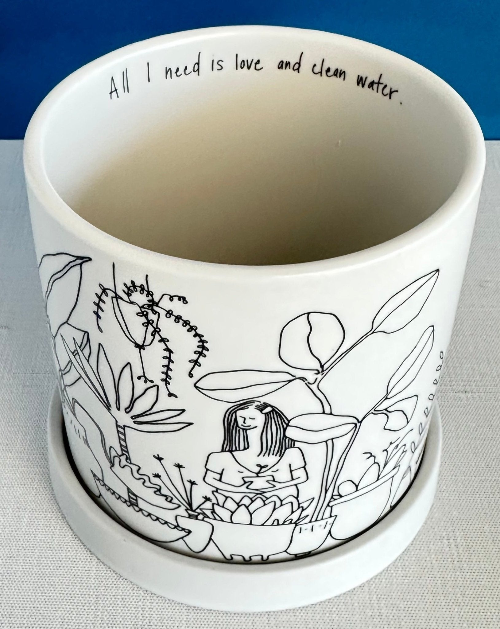 this large whimsical planter pot is covered with an illustrated jungle scene featuring all types of houseplants.  A secret message sits on the rim inside: All I need is a little love and clean water