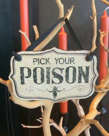 This set of two Halloween ornaments features two decorative hanging signs that reads 'PICK YOUR POISON' in distressed black lettering on an off-white background, suspended by a black ribbon.