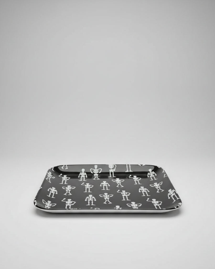 A square ceramic black appetizer tray with rounded corners, featuring a repeating pattern of small white stick-figure skeletons. Approx. 8.25" square.