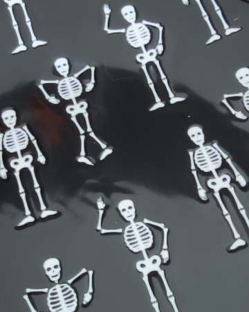 A square ceramic black appetizer tray with rounded corners, featuring a repeating pattern of small white stick-figure skeletons. Approx. 8.25" square.