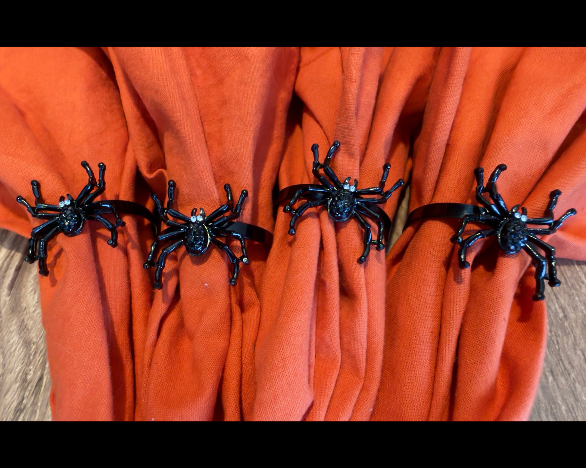 Set of Four black metal spider-shaped napkin rings with rhinestone accents for eyes.