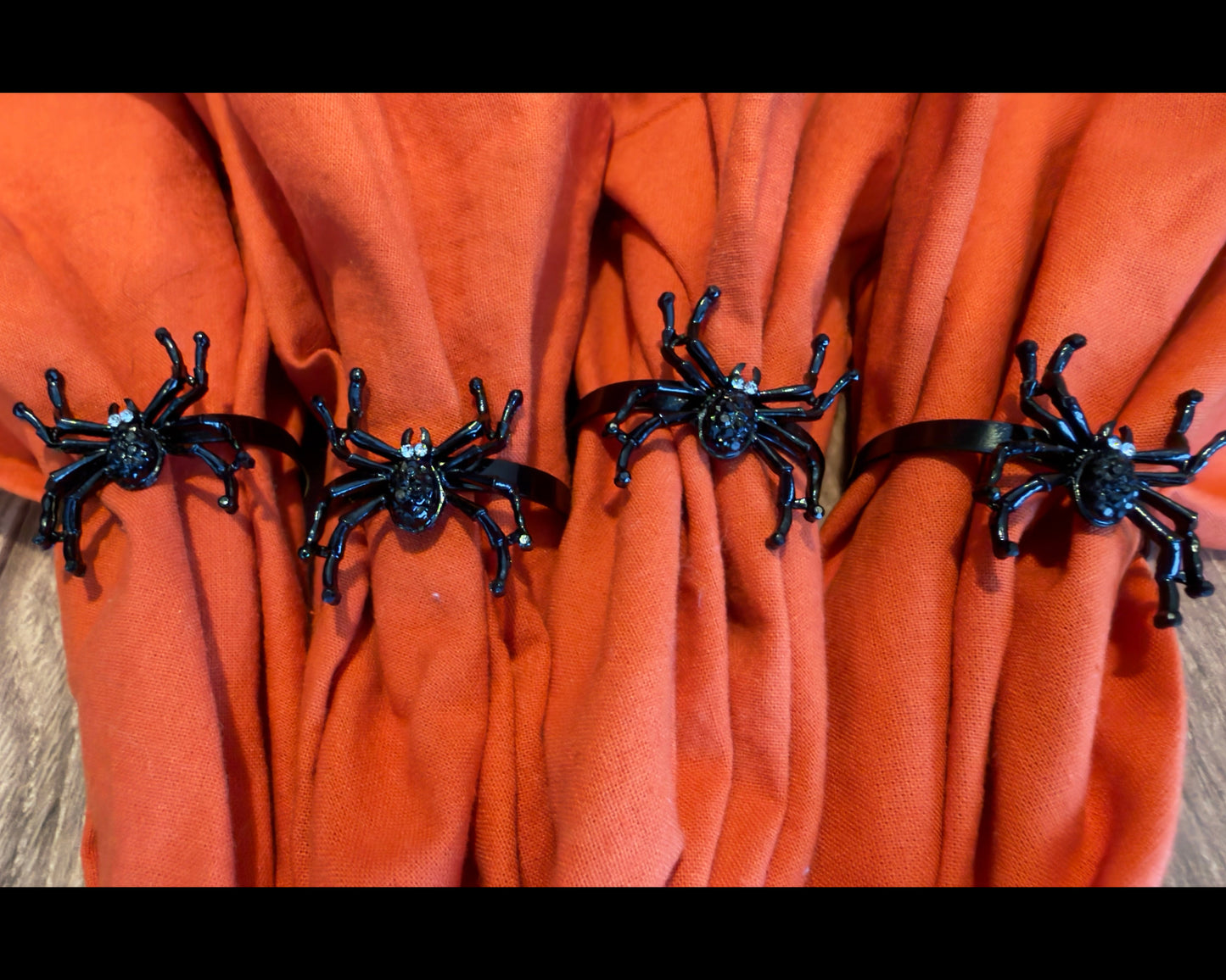 Set of Four black metal spider-shaped napkin rings with rhinestone accents for eyes.