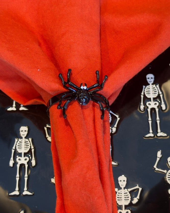 Set of Four black metal spider-shaped napkin rings with rhinestone accents for eyes.