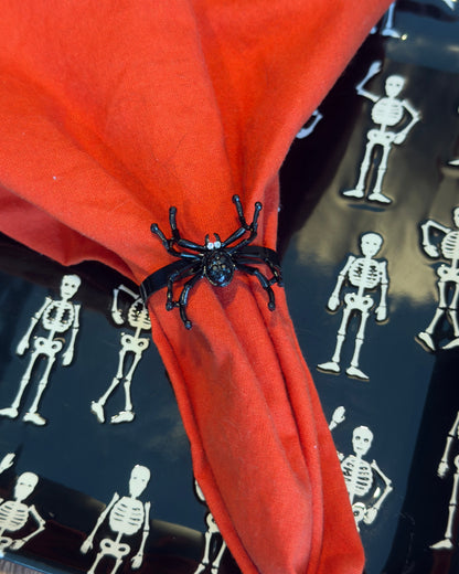 Set of Four black metal spider-shaped napkin rings with rhinestone accents for eyes.