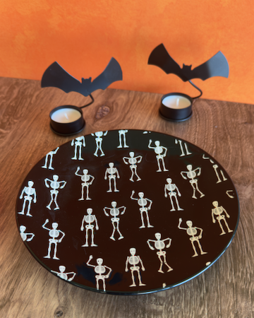 This quirky, fun Halloween Salad Plate is a round black ceramic plate with a repeating white pattern of small dancing skeletons. Approx. 8.5" round.