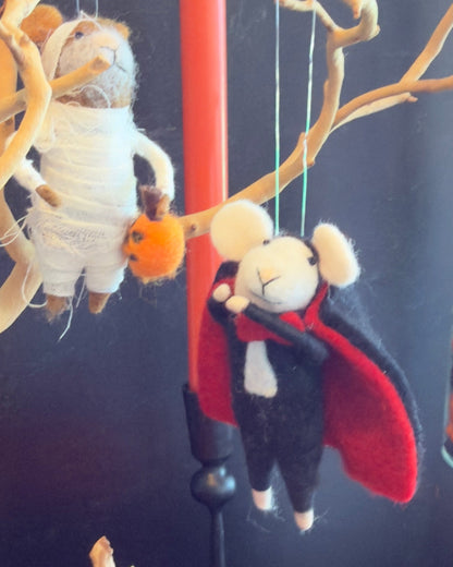 A felted wool vampire mouse hanging from a branch, wearing a black suit, white collar, and red cape. Approx 6" tall.