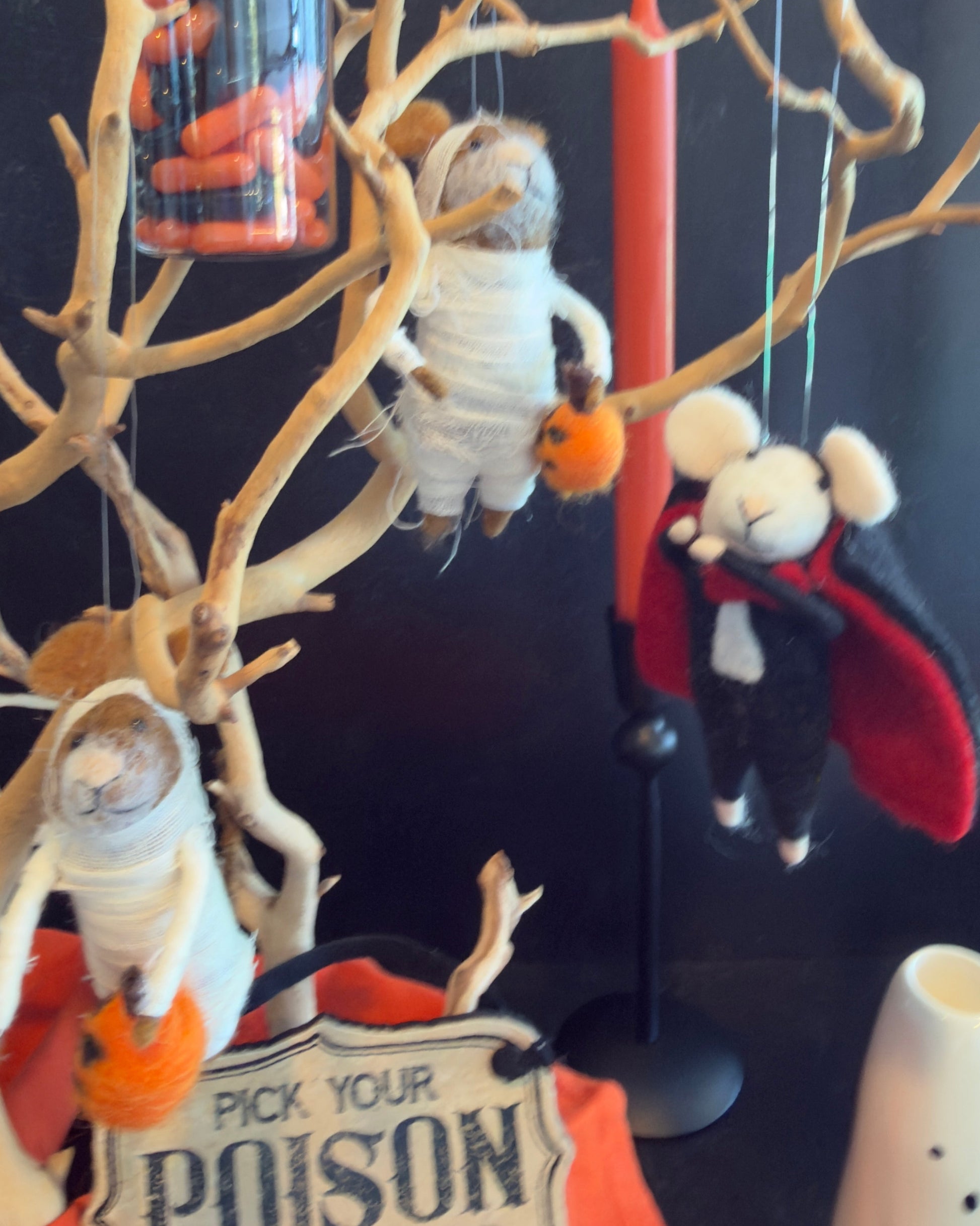 A felted wool vampire mouse hanging from a branch, wearing a black suit, white collar, and red cape. Approx 6" tall.